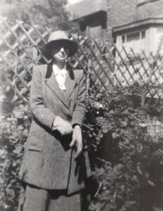 Black and white photograph of a woman standing in a garden.