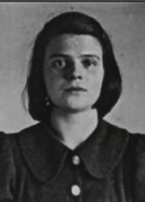 Black and white photograph of a teenage girl. She has dark bob length air and wears a dark blouse with a oversized collar. She has a serious and neutral expression.