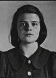 Black and white photograph of a teenage girl. She has dark bob length air and wears a dark blouse with a oversized collar. She has a serious and neutral expression.
