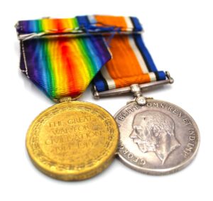 Photograph of two medals; one is gold with a rainbow coloured fabric attached, the other is a silver medal with purple and orange material